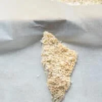 Fully coated perch fish placed on a parchment lined baking sheet