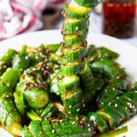 A chopstick stretching out a cucumber showing the twists and perfect dressing that's stuck all over the cucumber.