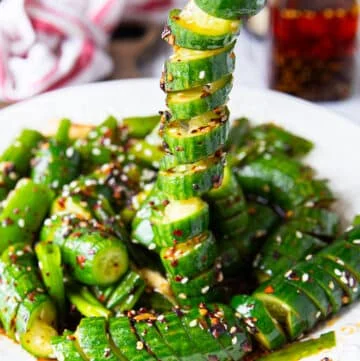 A chopstick stretching out a cucumber showing the twists and perfect dressing that's stuck all over the cucumber.