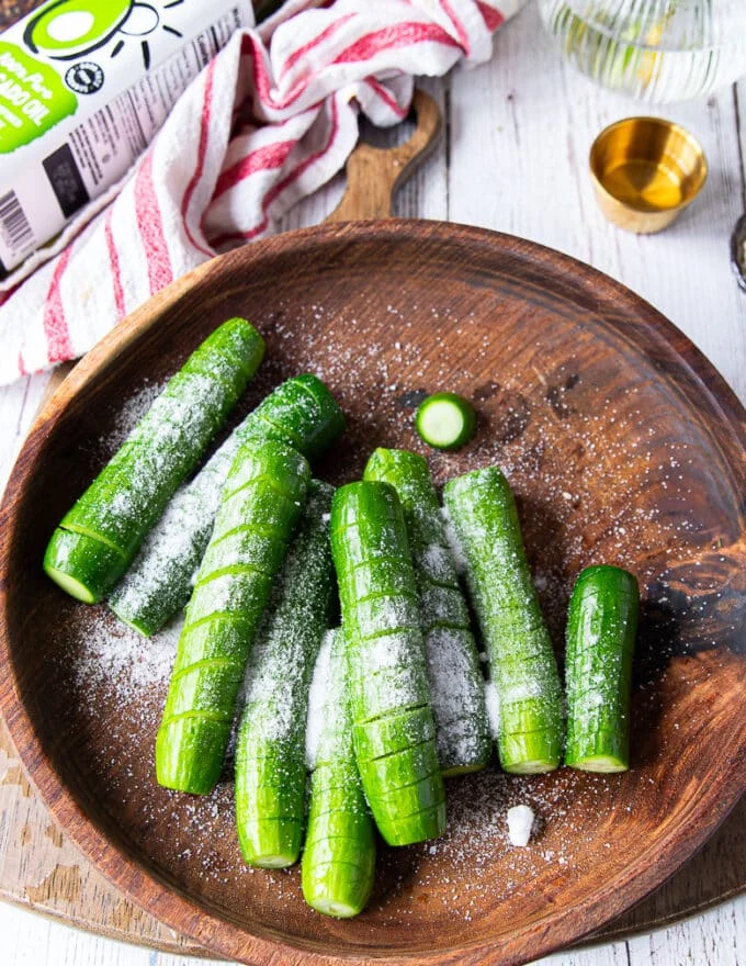 Salt added to the cut up cucumbers in a large bowl
