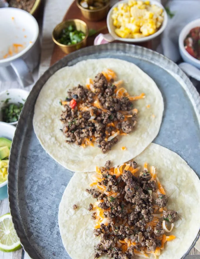 In a baking sheet, some soft tortillas are also layered with cheese and ground beef to show how you can make tacos with soft shells