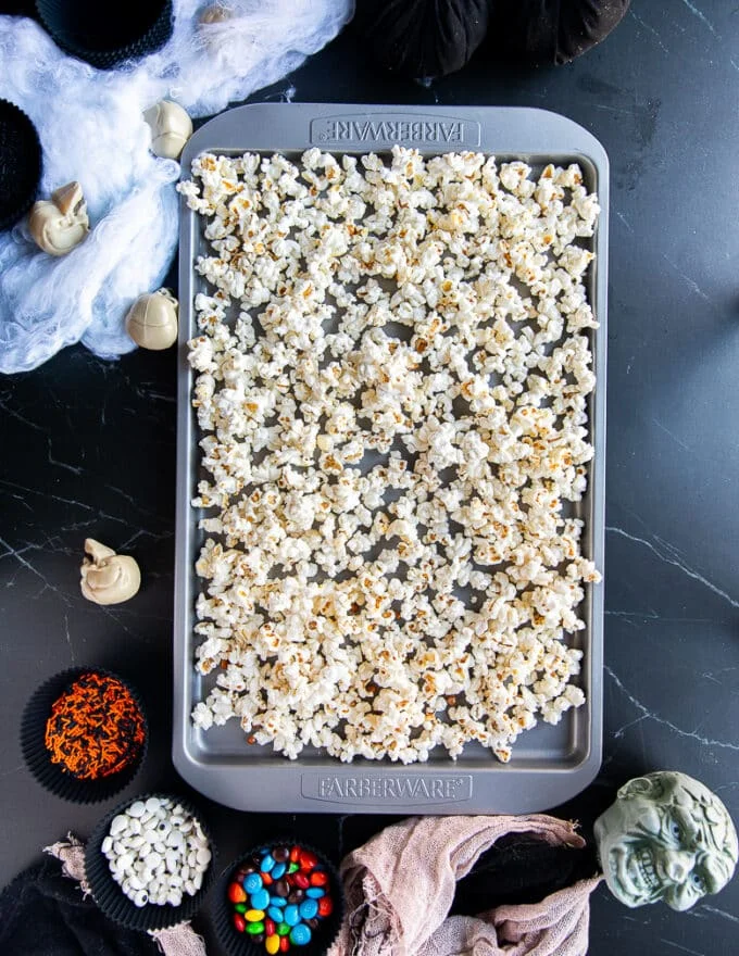 The popped popcorn spread in a baking sheet in a single layer
