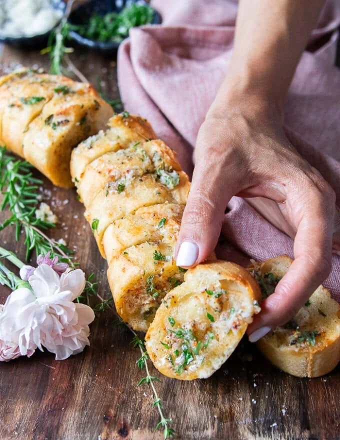 A hand holding one piece of air fryer garlic bread close up showing the texture and toppings