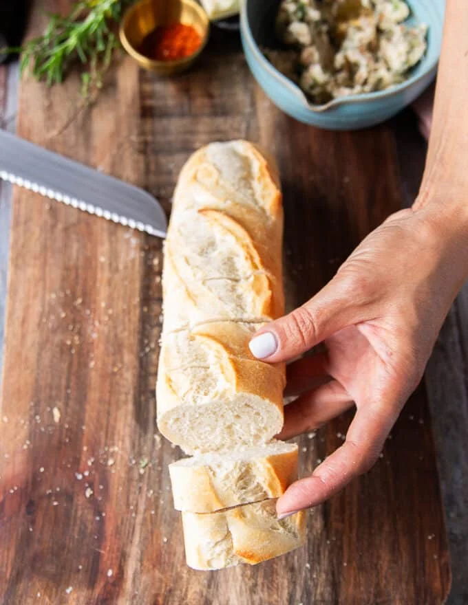 hand scorching the baguette into half inch slices not cuttiing all the way through and showing how to cut the bread
