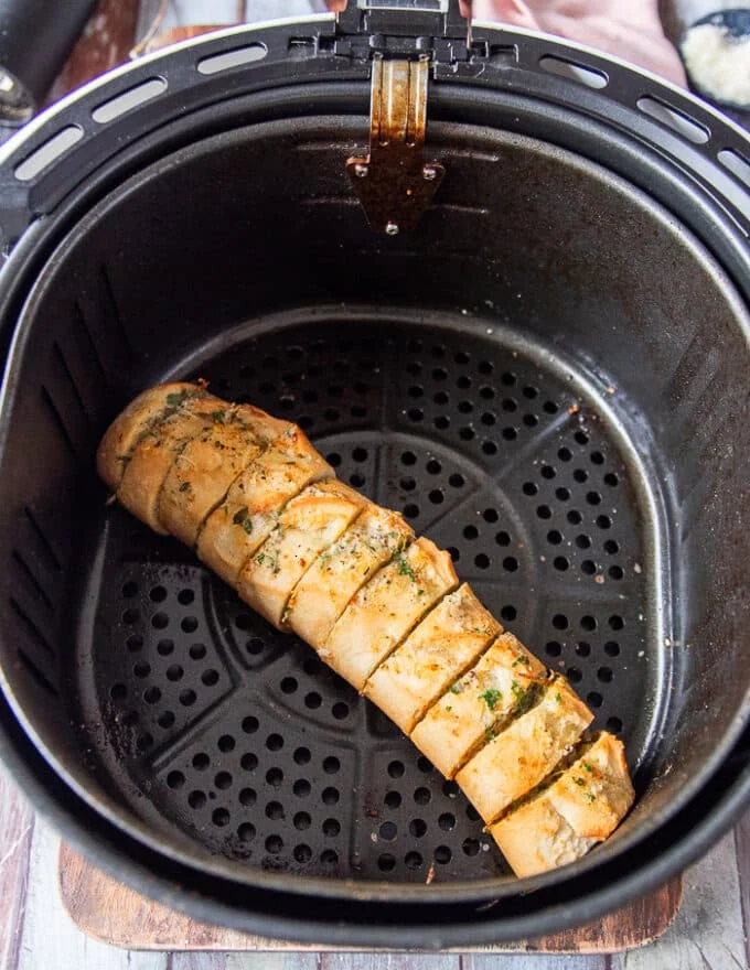 Slightly golden garlic bread in the air fryer basked ready and cooked in the air fryer