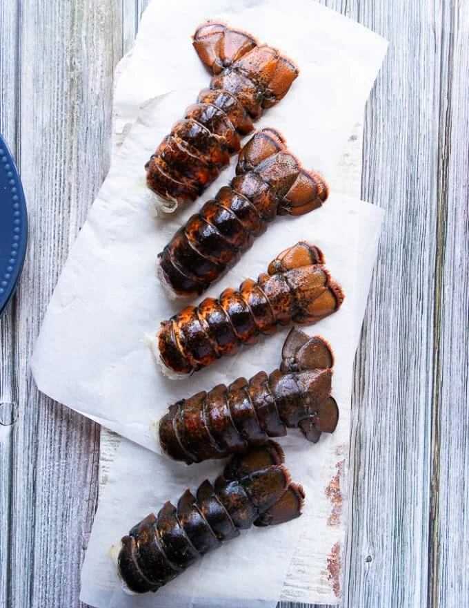 5 lobster tails on a wooden board to make butter poached lobster