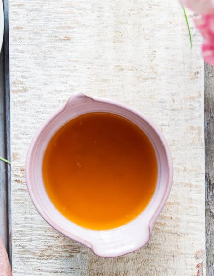A bowl with the strained butter sauce looking like liquid gold