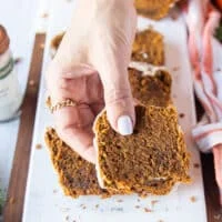 A hand holding a bitten piece of pumpkin bread recipe close up showing up the texture