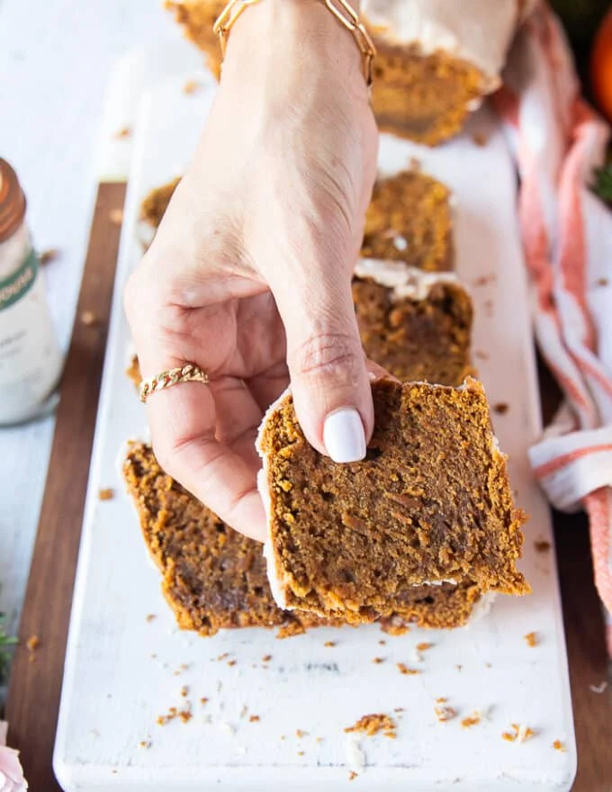 A hand holding a bitten piece of pumpkin bread recipe close up showing up the texture
