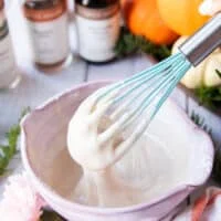 chai spice glaze ingredients all mixed in a bowl using a whisk and the whisk showing how thick it is