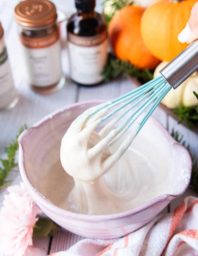 chai spice glaze ingredients all mixed in a bowl using a whisk and the whisk showing how thick it is