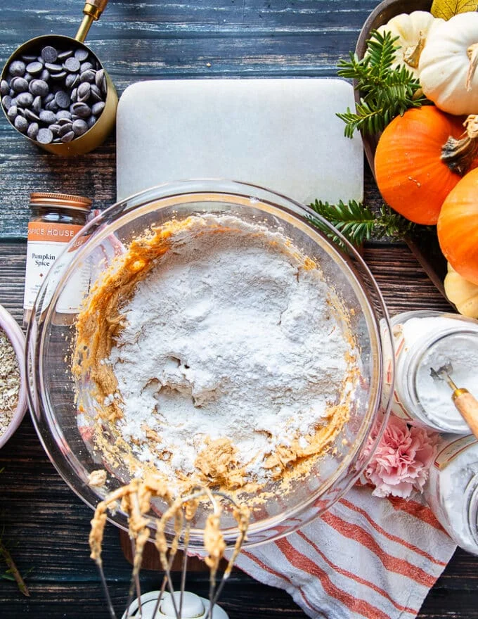 flour, baking soda and salt are added to the bowl to pumpkin oatmeal cookie batter