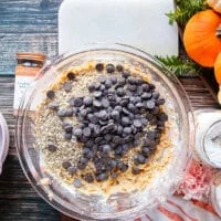 Oatmeal and chocolate chunks are added over the plate of cookie batter