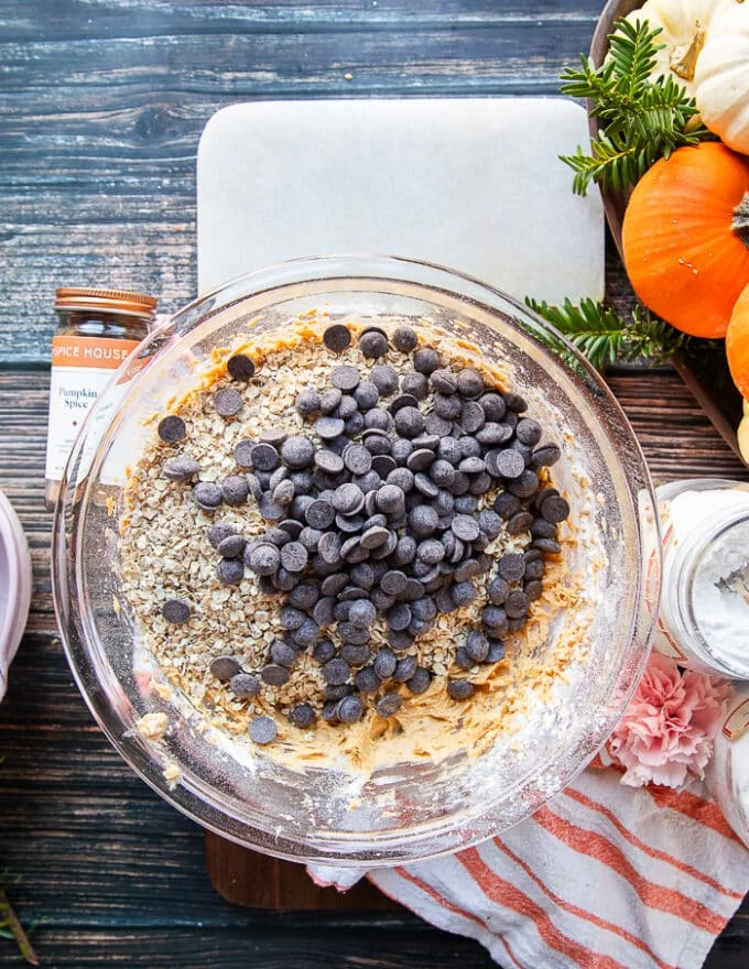 Oatmeal and chocolate chunks are added over the plate of cookie batter