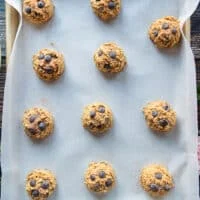 Scooped pumpkin oatmeal chocolate chip cookies on a baking sheet ready to bake