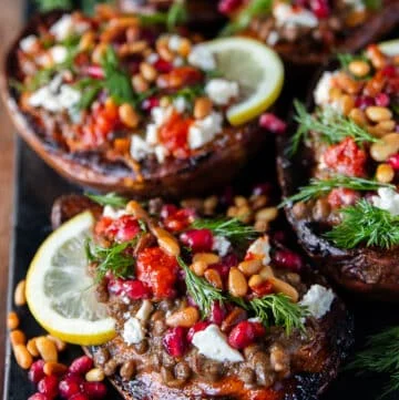 close up of one stuffed sweet potato showing the texture of the roasted sweet potatoes so soft and loaded with filling like lentils, pomegranates , hot sauce, fresh herbs, feta cheese