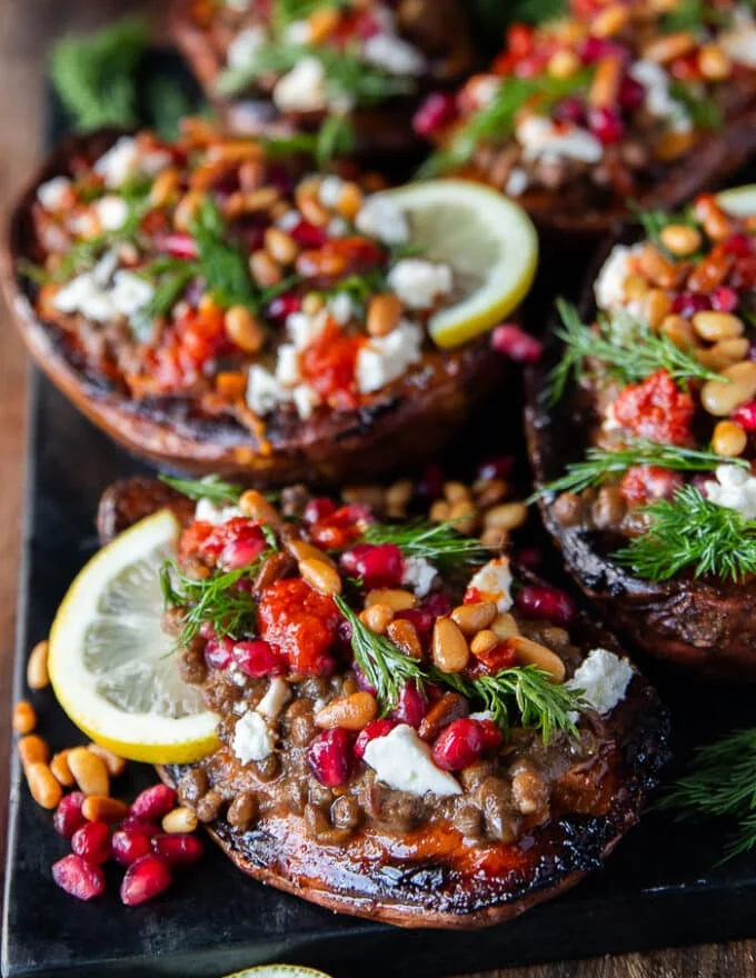 close up of one stuffed sweet potato showing the texture of the roasted sweet potatoes so soft and loaded with filling like lentils, pomegranates , hot sauce, fresh herbs, feta cheese