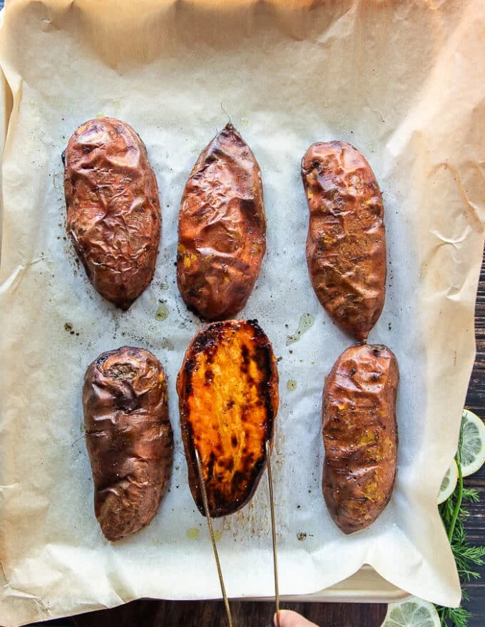sweet potatoes perfectly roasted and out of the oven, one half is flipped the other side to show the caramelized top and how perfectly cooked it is