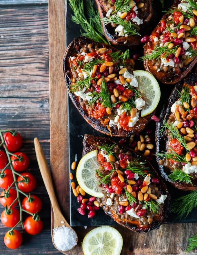A full plate of stuffed sweet potatoes all garnished and stuffed ready to serve. The plate is garnished with dill, lemon slices and baby tomatoes.
