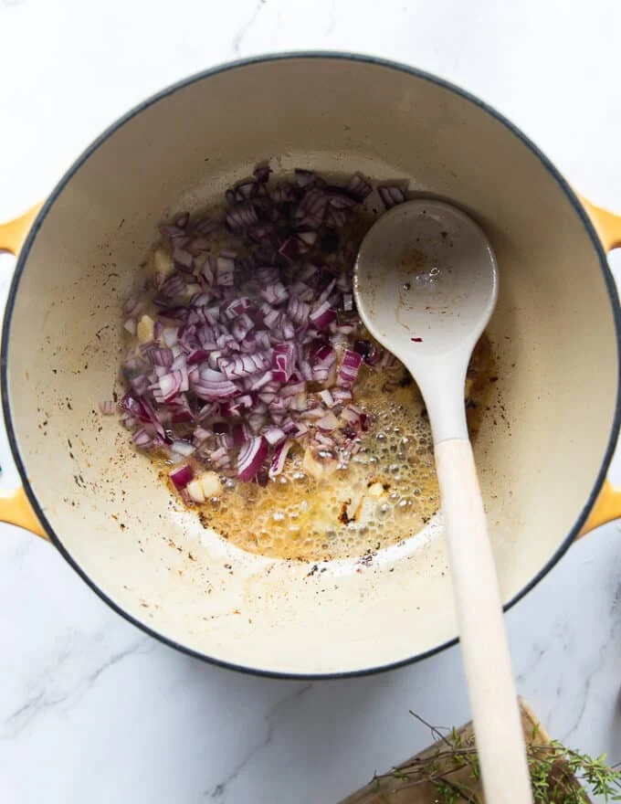 Onions are added into the same pot to start making the sauce