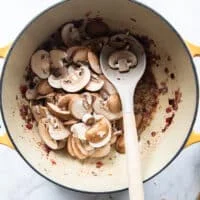 sliced cremini mushrooms are added to the pot of onions