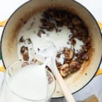 A hand pouring the milk and half n half into the pot