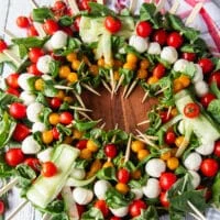 The full caprese wreath over a bed of basil leaves with the center empty. Optional to put the dressing in the middle or leave it as is