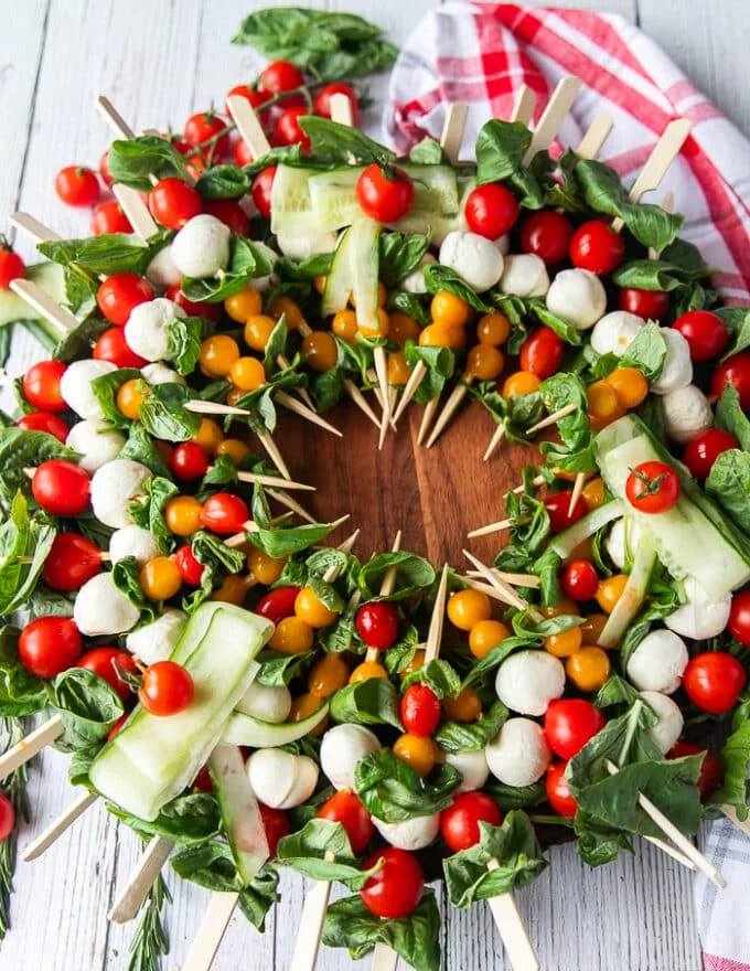 The full caprese wreath over a bed of basil leaves with the center empty. Optional to put the dressing in the middle or leave it as is