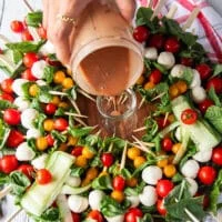 The simple balsamic olive oil dressing is poured into a small jar in the middle of the caprese wreath