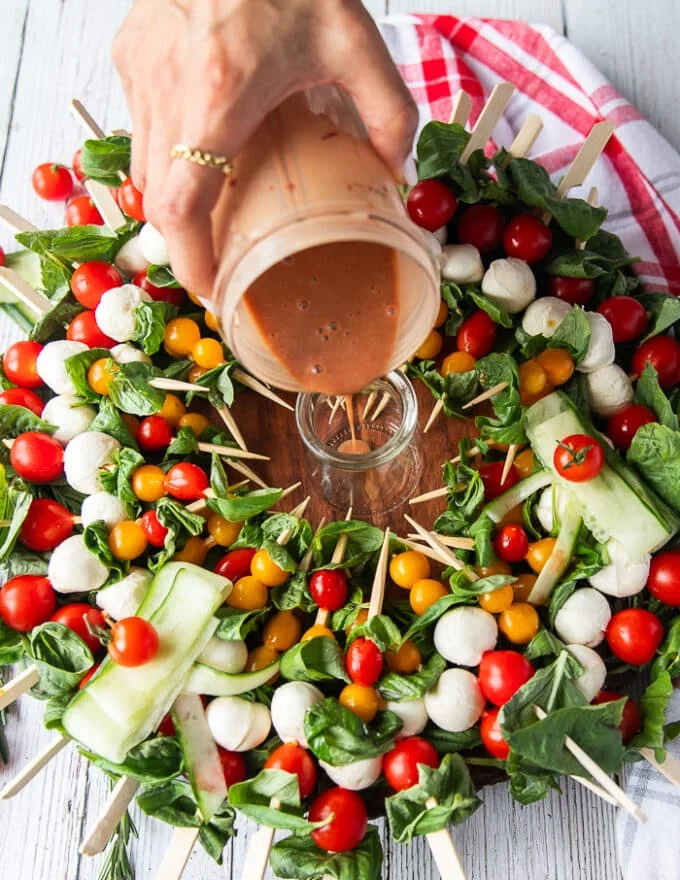 The simple balsamic olive oil dressing is poured into a small jar in the middle of the caprese wreath