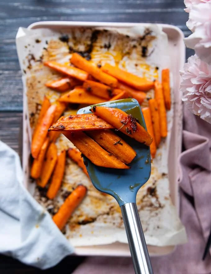 A spoon showing the carrots ready and glazed close up to the camera