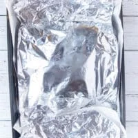 the lamb shoulder is covered in foil and ready to roast