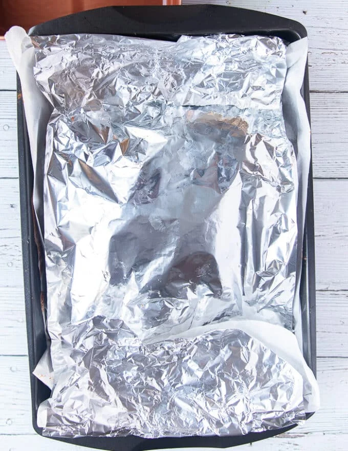the lamb shoulder is covered in foil and ready to roast