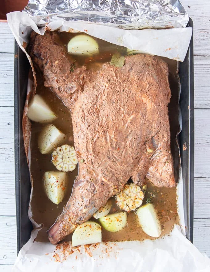 The stock is poured around the lamb shoulder and ready to roast