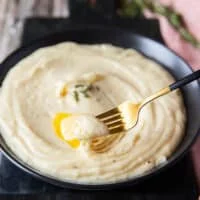 A fork spooning out some of the mashed potatoes with the melted butter on top showing the creamy texture.