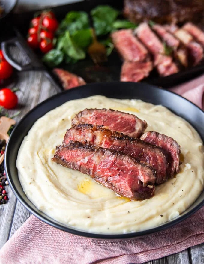 3 pieces of steak cut up over the mashed potatoes dish for a serving suggestion
