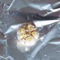 a head of garlic with the tops cut off in the middle of some foil. Drizzled with olive oil and sea salt