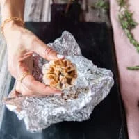 a roasted head of garlic just ready and unwrapped from the foil looking golden and super soft
