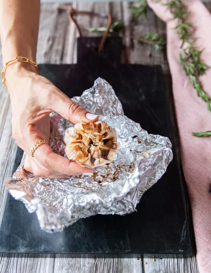 a roasted head of garlic just ready and unwrapped from the foil looking golden and super soft