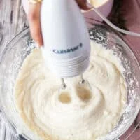 A hand holding a hand mixer and using it to fluff up the potatoes and mash them instead of a potato masher