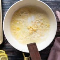 A skillet with butter and garlic sautéing