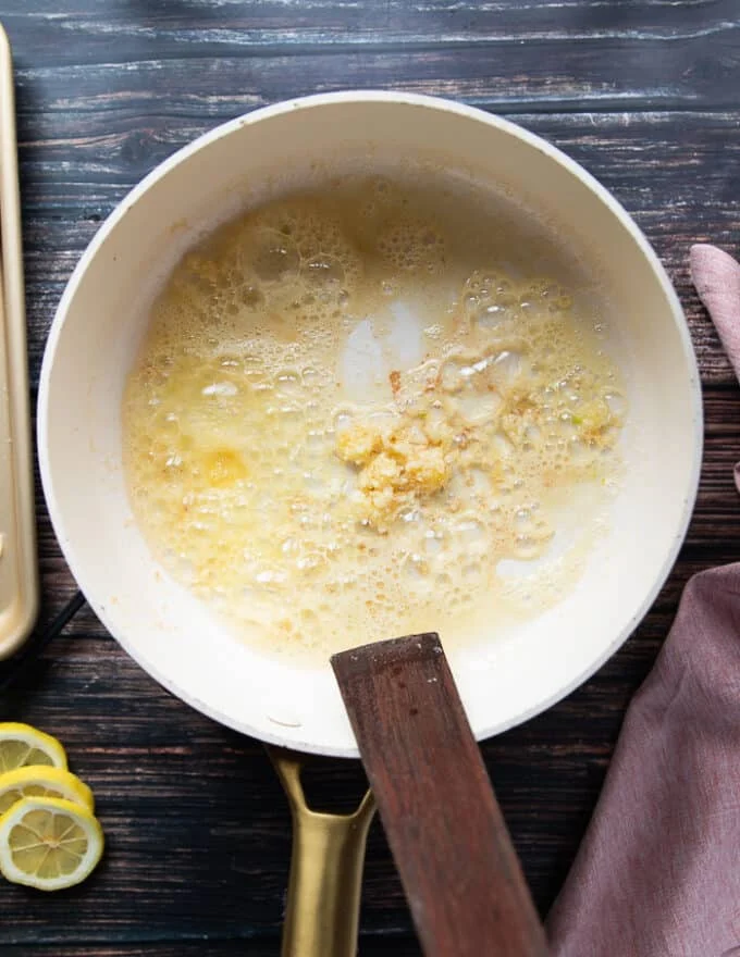 A skillet with butter and garlic sautéing