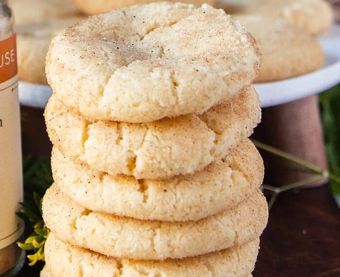 Long stack of 6 sugar cookies on top of each other showing the texture and specs of vanilla bean on a wooden board
