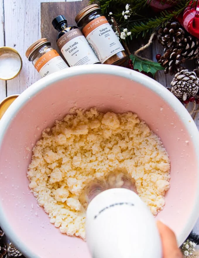 The mixer is blending the butter and sugar in a large bowl to make the sugar cookie dough