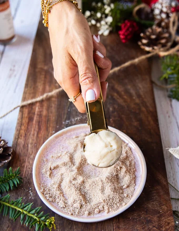 A hand scooping 1 inch size sugar cookie dough