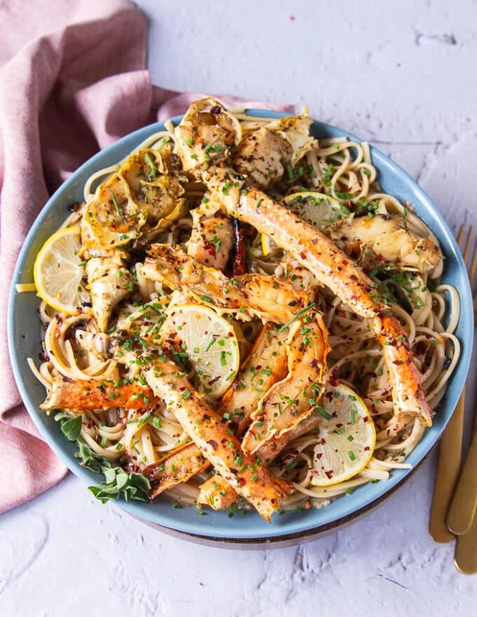 top view of a plate of crab pasta with some silverware on the side