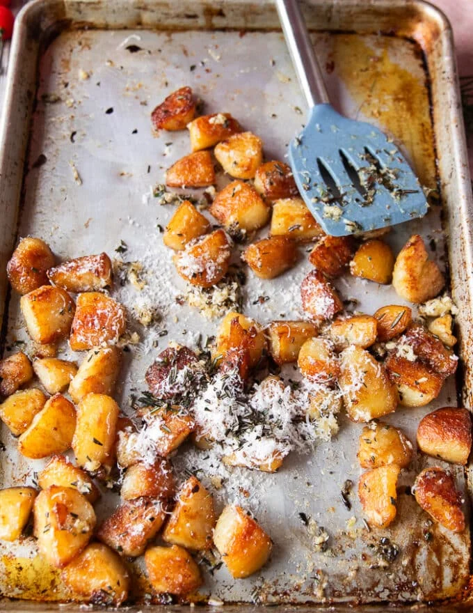 rosemary, minced garlic and parmesan are added to the ready potatoes in the baking sheet for seasoning and flavoring them