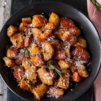 Top view close up of crispy potatoes showing the deep golden color and crisp outside of the roasted potatoes and some rosemary and parmesan on top