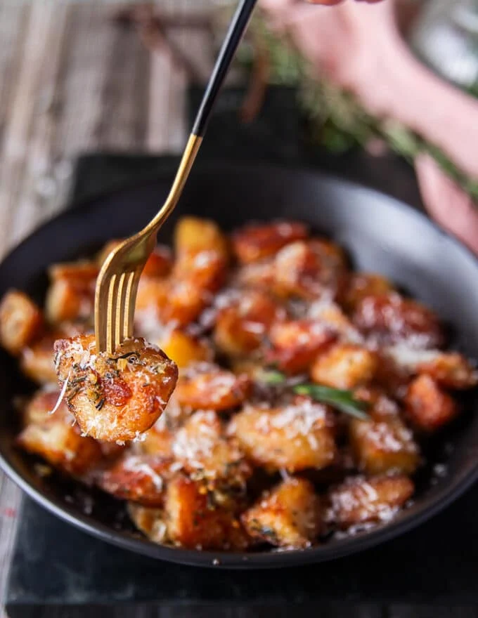a fork showing close up of one crispy potato and how crisp and golden it is