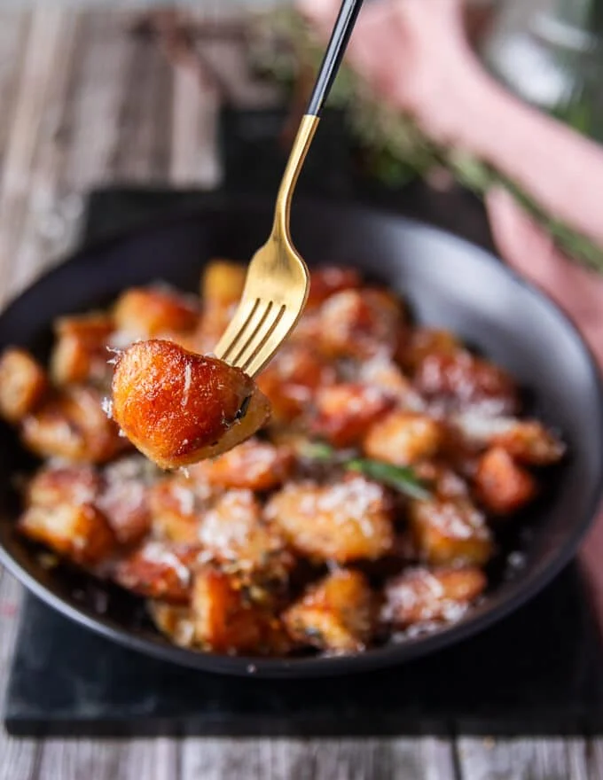 Fork holding some crispy potatoes up close showing the texture and browning